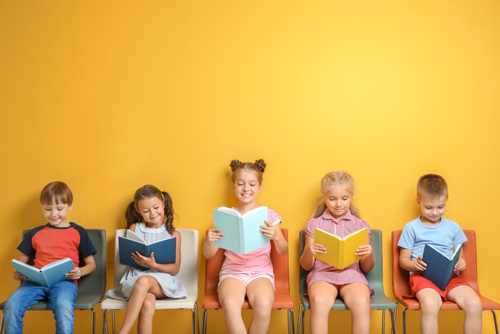 dzieci siedzą i czytają książkę na żółtym tle