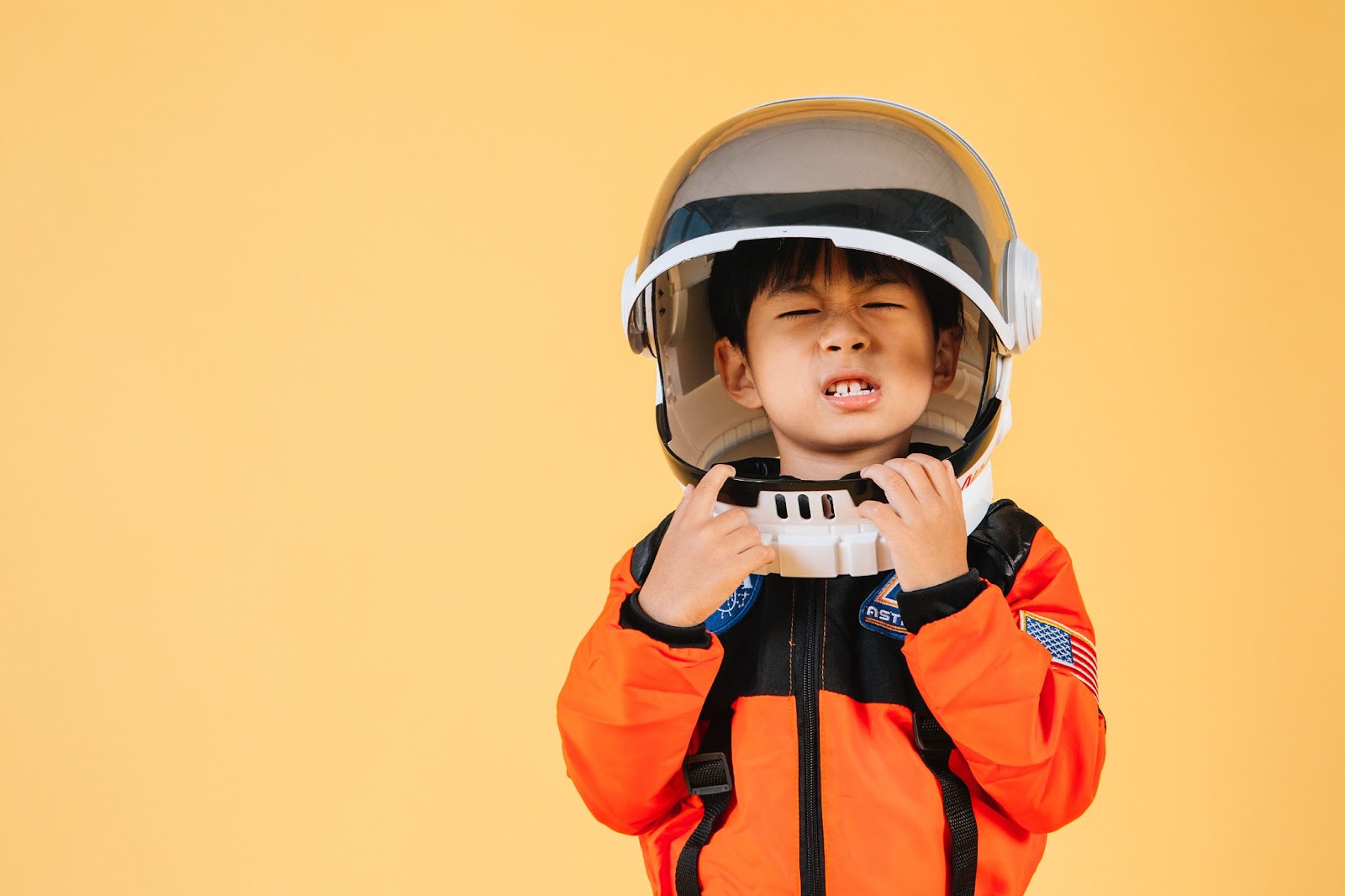 chłopiec w kostiumie astronauty na żółtym tle